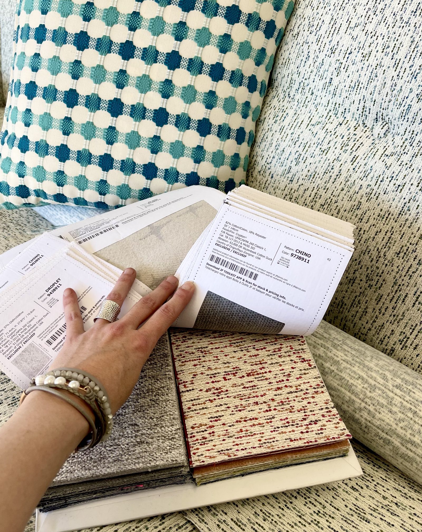 Fabric book with swatches open on a couch cushion, a hand turning the pages